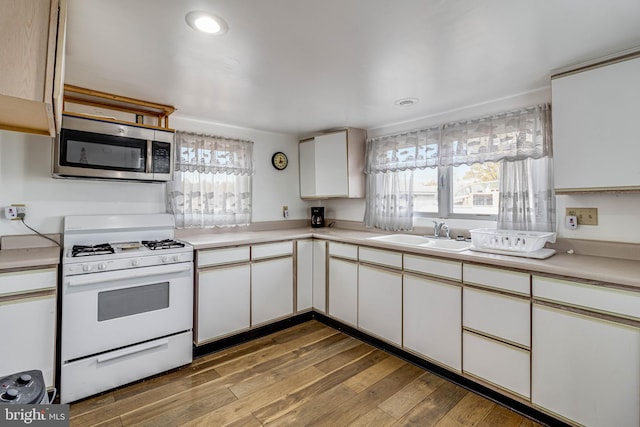 kitchen featuring white cabinetry, wood-type flooring, white range with gas cooktop, and sink