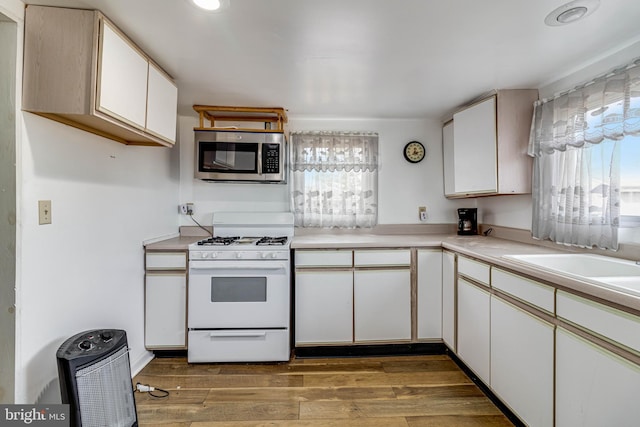 kitchen featuring white cabinetry, sink, wood-type flooring, and white range with gas stovetop