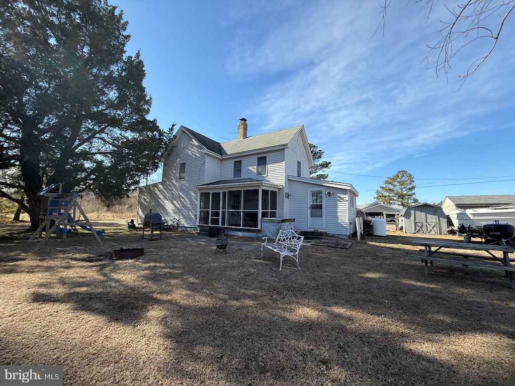 back of house featuring a playground and a sunroom