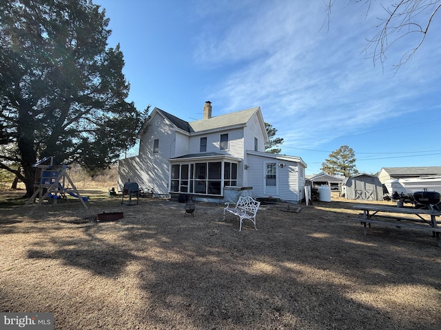 rear view of house with a playground and a sunroom