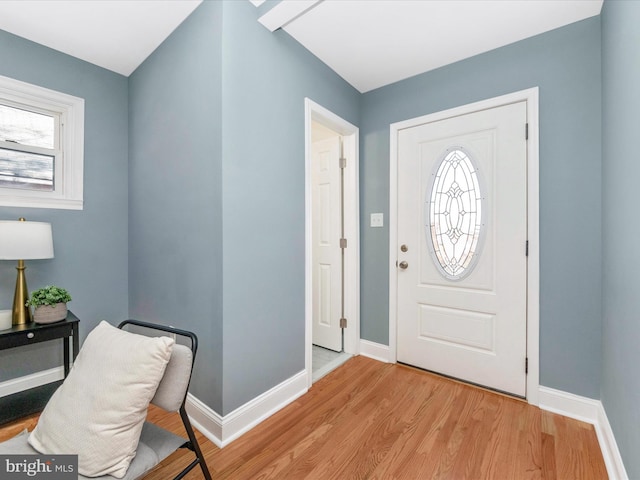 entrance foyer with baseboards, a healthy amount of sunlight, and light wood-style flooring