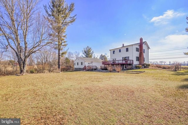 back of property featuring a yard, a chimney, and a wooden deck