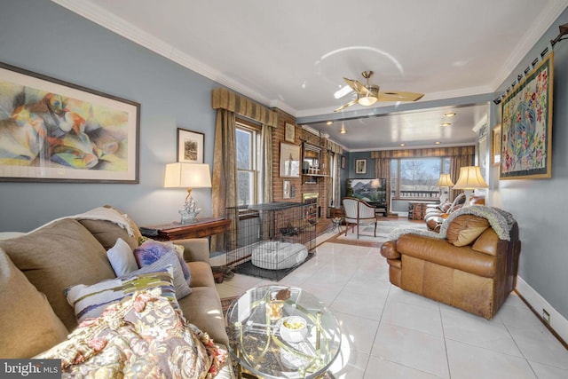 living room with light tile patterned floors, baseboards, a ceiling fan, crown molding, and a brick fireplace