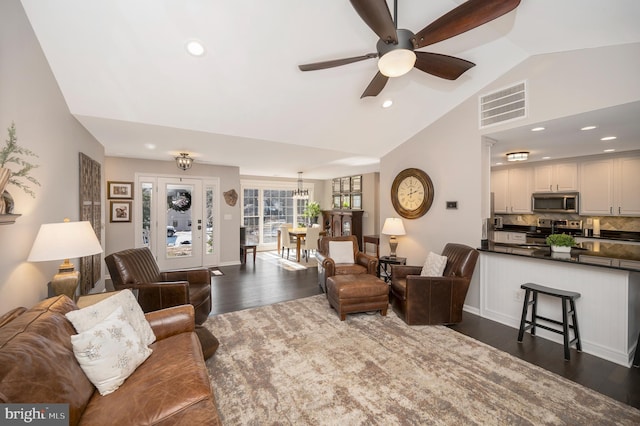 living room featuring vaulted ceiling, dark hardwood / wood-style floors, and ceiling fan with notable chandelier