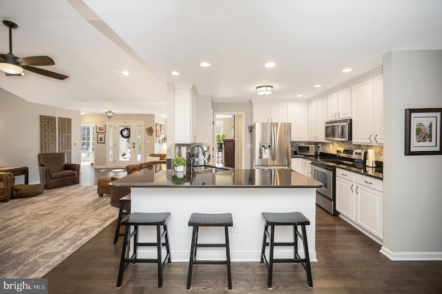 kitchen with sink, white cabinetry, a kitchen breakfast bar, stainless steel appliances, and kitchen peninsula