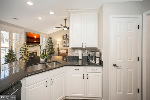 kitchen featuring sink, vaulted ceiling, kitchen peninsula, dishwasher, and white cabinets