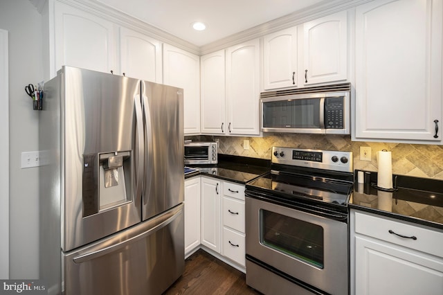 kitchen with backsplash, stainless steel appliances, dark stone counters, and white cabinets