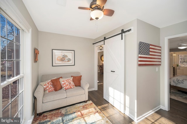 living room featuring a barn door, dark wood-type flooring, and ceiling fan