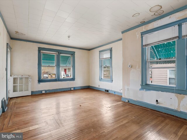 empty room with hardwood / wood-style floors and crown molding