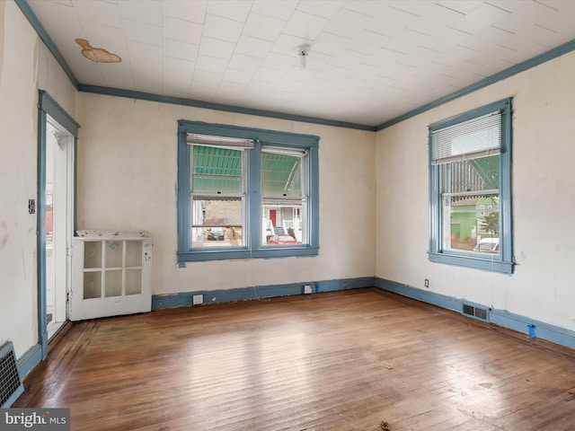 empty room with crown molding and wood-type flooring