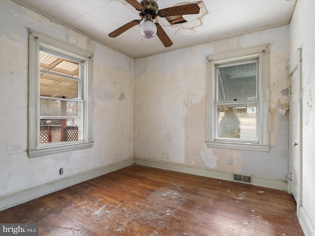 spare room featuring ceiling fan, a healthy amount of sunlight, and dark hardwood / wood-style flooring