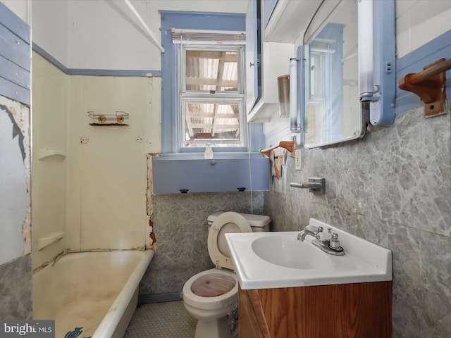 bathroom with vanity, toilet, a bath, and tile walls