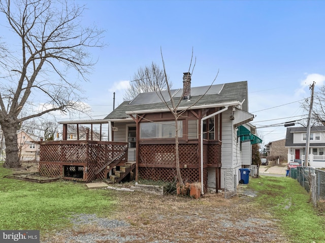 rear view of property with a wooden deck and a lawn