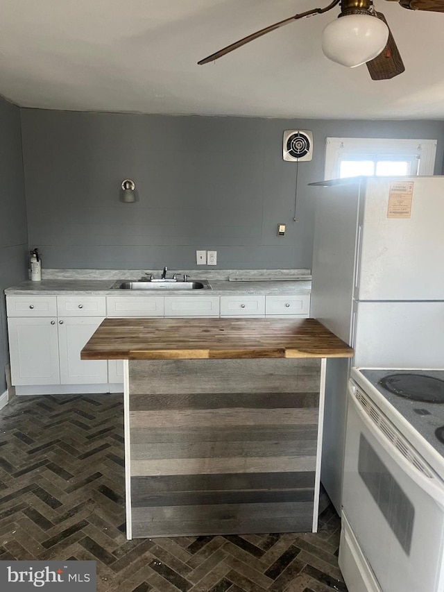 kitchen with butcher block counters, sink, white appliances, and white cabinets