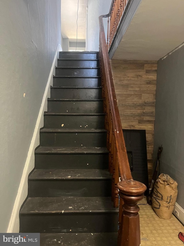 staircase featuring wooden walls