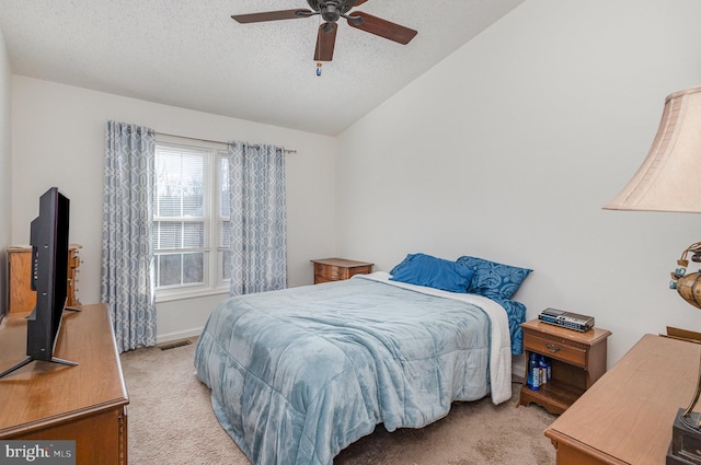 bedroom with ceiling fan, light colored carpet, vaulted ceiling, and a textured ceiling