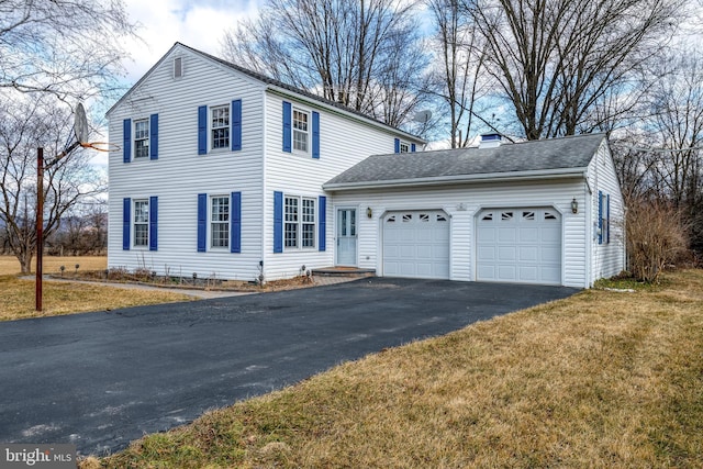 view of front of property featuring aphalt driveway, roof with shingles, a chimney, a front yard, and a garage