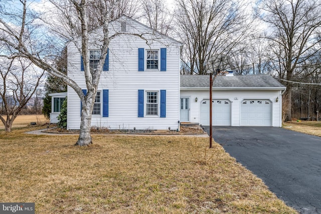 view of front of house featuring a garage, driveway, a front lawn, and roof with shingles