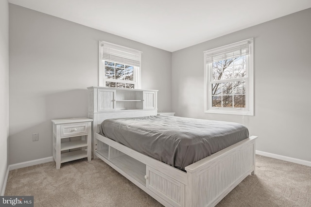 carpeted bedroom featuring multiple windows and baseboards