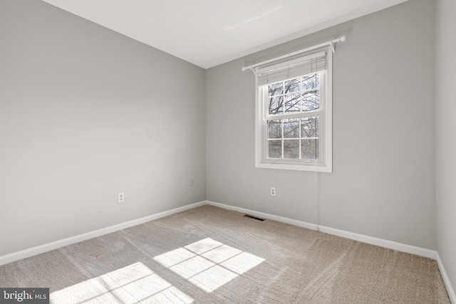 empty room featuring light carpet, visible vents, and baseboards