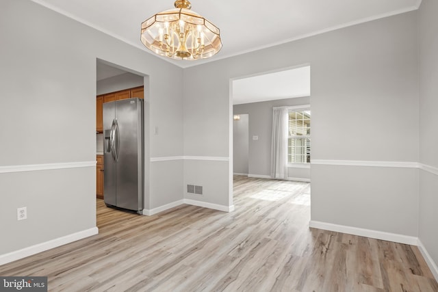 unfurnished dining area with light wood-style floors, visible vents, ornamental molding, and baseboards