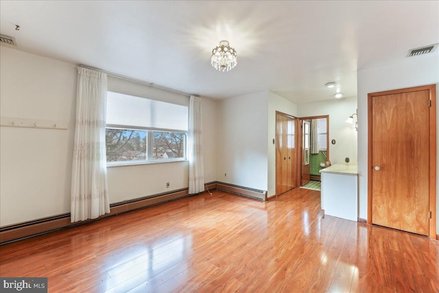 empty room with light hardwood / wood-style floors and baseboard heating