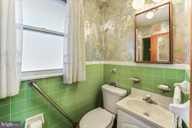 bathroom with plenty of natural light, toilet, vanity, and tile walls