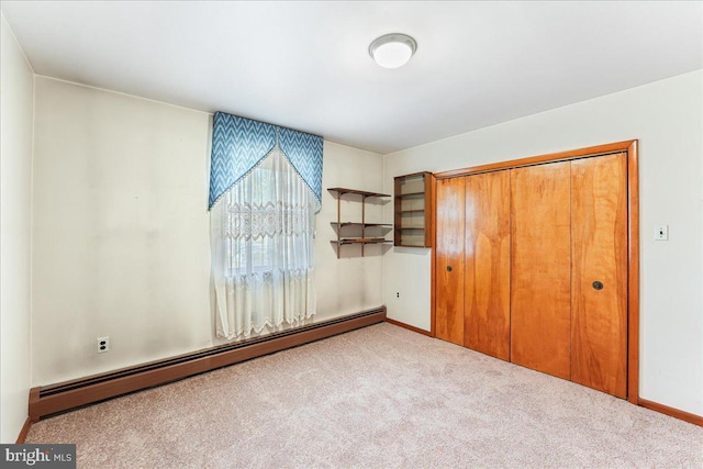 unfurnished bedroom featuring a baseboard heating unit, light colored carpet, and a closet