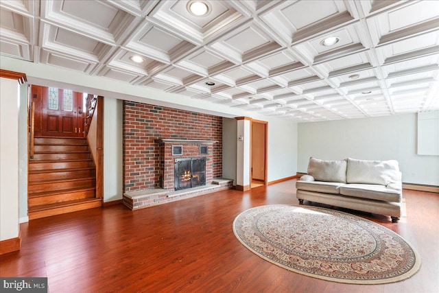 living room with baseboard heating, wood-type flooring, a fireplace, and coffered ceiling