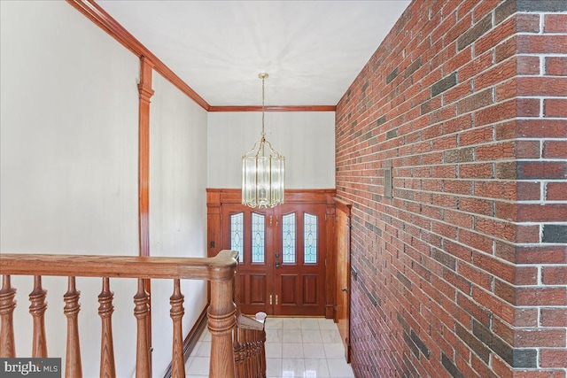 entryway featuring ornamental molding, brick wall, light tile patterned floors, and a chandelier