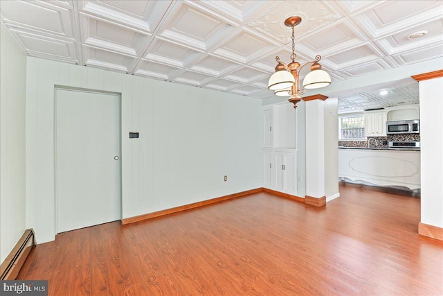 unfurnished living room with an inviting chandelier, a baseboard heating unit, coffered ceiling, and hardwood / wood-style floors