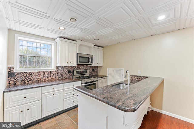 kitchen with stainless steel appliances, white cabinets, a kitchen bar, and kitchen peninsula