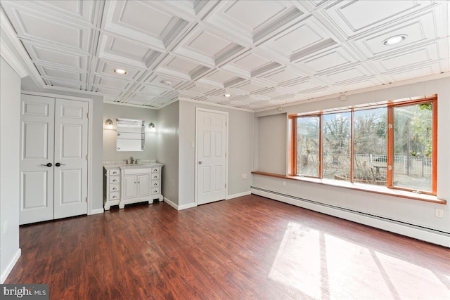 unfurnished bedroom featuring baseboard heating, dark hardwood / wood-style floors, and sink