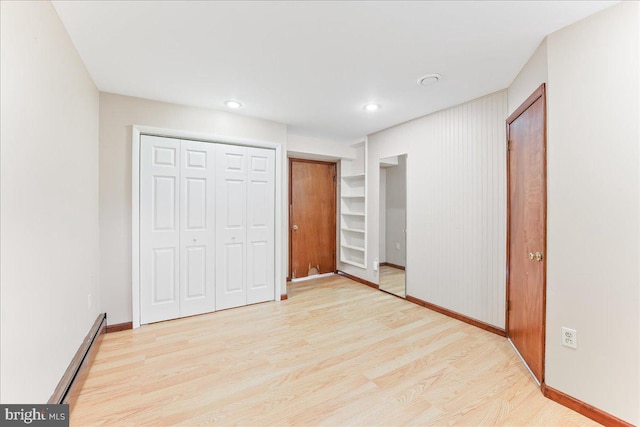 unfurnished bedroom featuring light hardwood / wood-style flooring, a closet, and a baseboard radiator