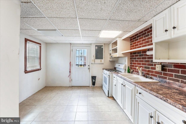 kitchen featuring a paneled ceiling, sink, white cabinets, dark stone counters, and white gas stove