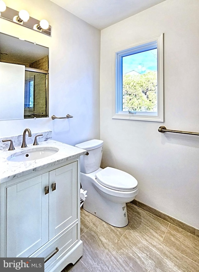 bathroom with walk in shower, vanity, and toilet