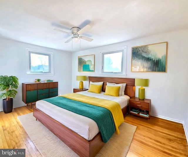 bedroom featuring ceiling fan, light hardwood / wood-style floors, and multiple windows