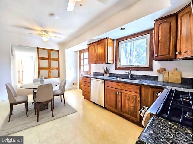 kitchen featuring sink, dark stone countertops, stainless steel dishwasher, ceiling fan, and gas range oven