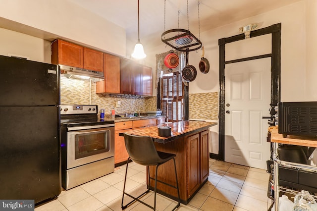 kitchen with a kitchen bar, black fridge, stainless steel electric range oven, light tile patterned floors, and a kitchen island