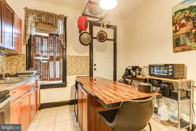 kitchen with tasteful backsplash, wooden counters, sink, and light tile patterned floors