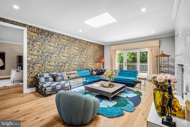 living room featuring crown molding, wood-type flooring, a large fireplace, and a skylight