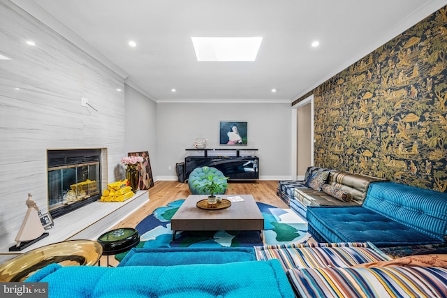 living room featuring ornamental molding, a large fireplace, light hardwood / wood-style flooring, and a skylight