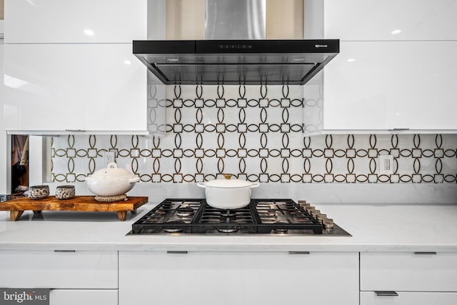 room details with white cabinetry, backsplash, stainless steel gas stovetop, and wall chimney exhaust hood