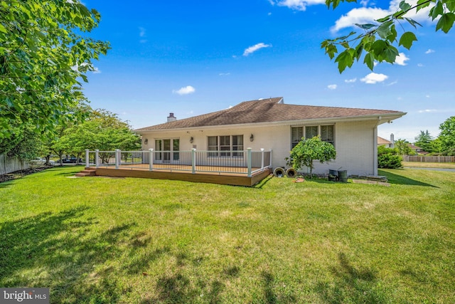 rear view of house with a wooden deck and a yard