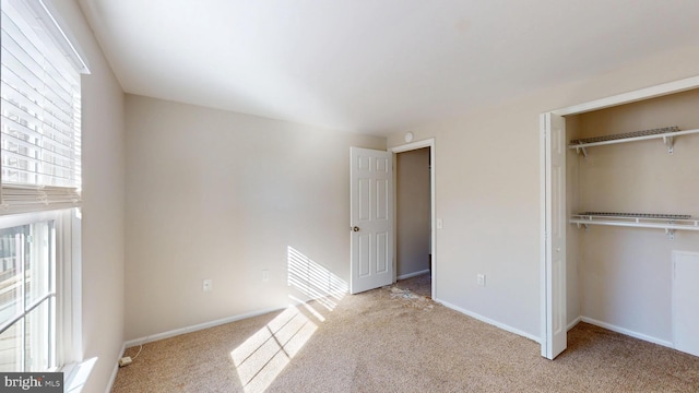 unfurnished bedroom featuring a closet, a walk in closet, and light colored carpet