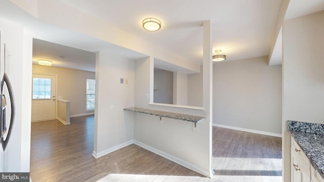 kitchen with white cabinets, stainless steel refrigerator with ice dispenser, dark stone counters, and hardwood / wood-style floors