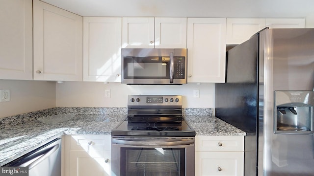 kitchen featuring white cabinets, appliances with stainless steel finishes, and light stone counters