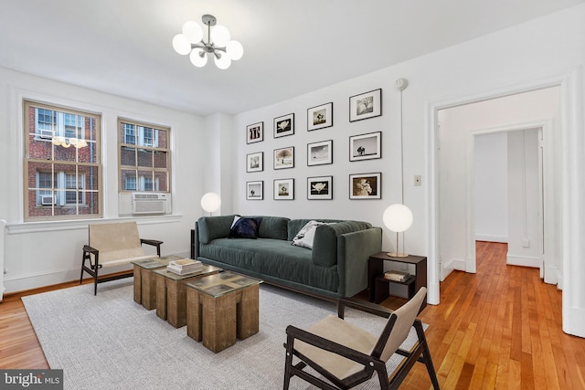 living room with cooling unit, a notable chandelier, and light hardwood / wood-style flooring