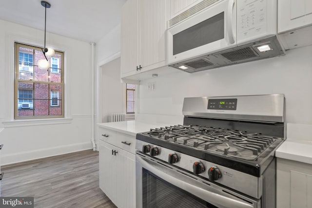 kitchen with white cabinetry, gas range, decorative light fixtures, and hardwood / wood-style flooring