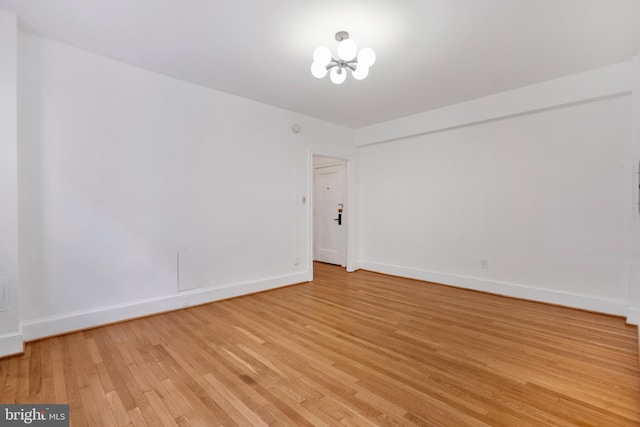 unfurnished room with a chandelier and light hardwood / wood-style floors